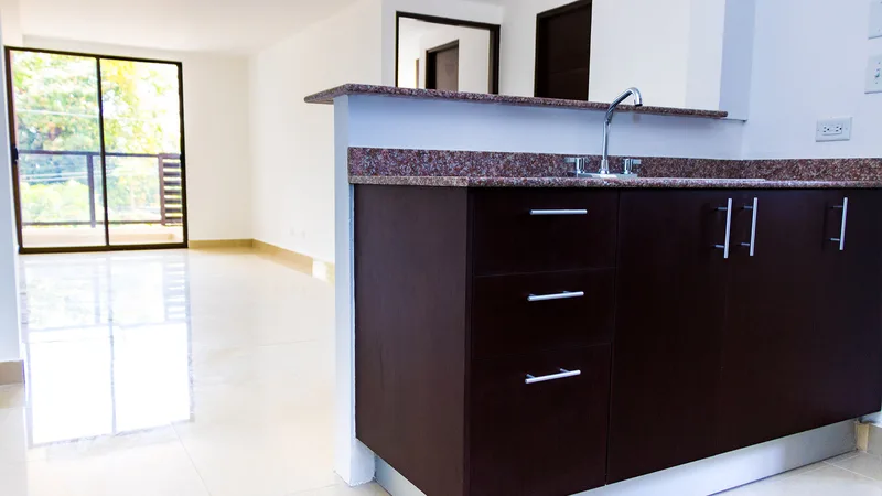 Cocina con desayunador de granito y muebles de madera oscura en un apartamento de Acacias Juan Díaz