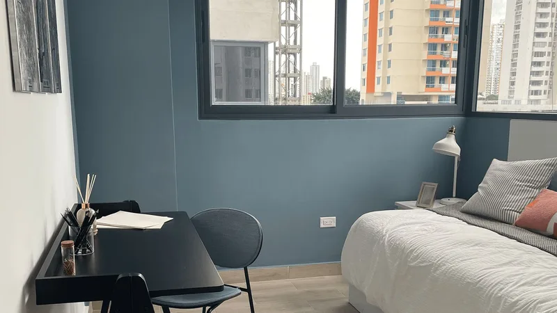 Recámara del apartamento modelo de Sky 66 con ventanales y vista a la ciudad